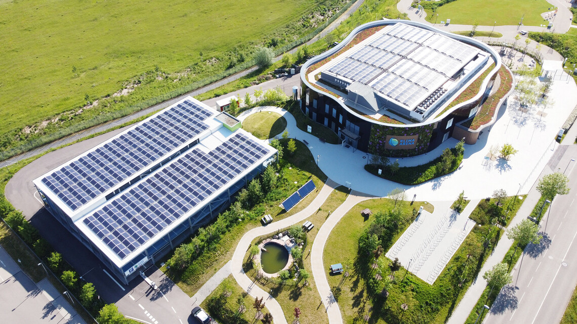 Luftbild auf das Geb&auml;ude und Parkgarage der KLIMA ARENA mit PV-Anlage.