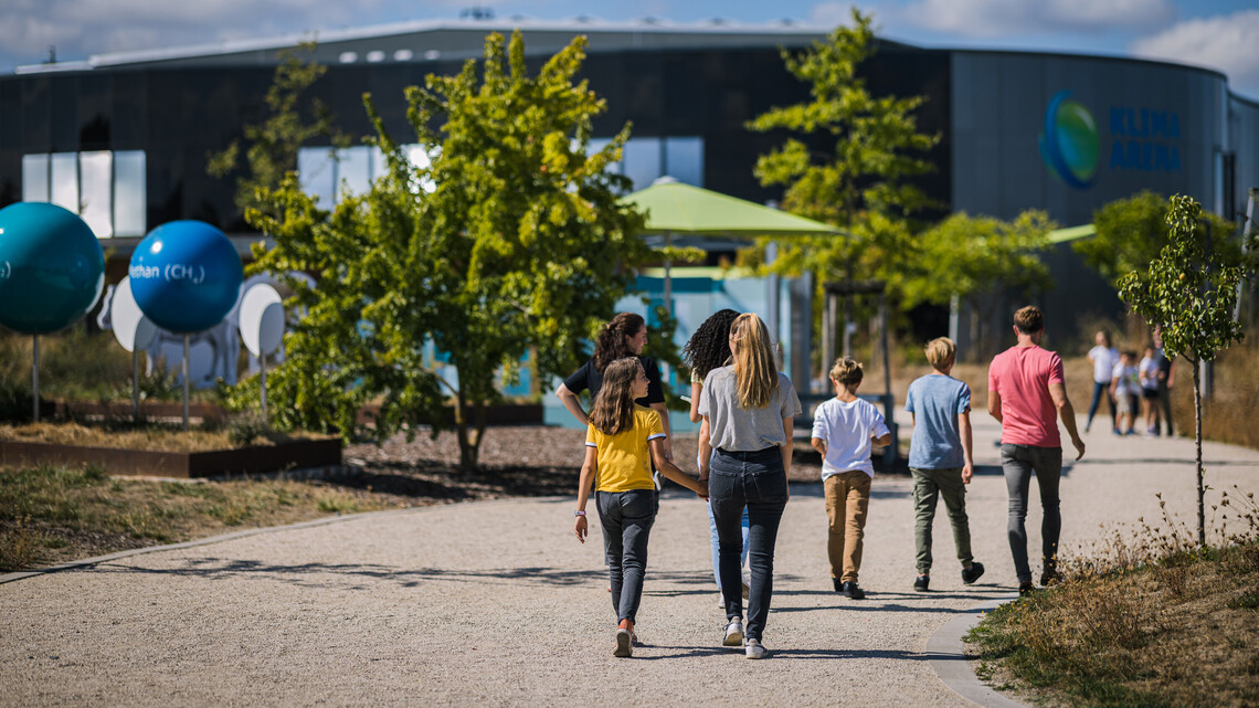 Familie l&auml;uft durch den Themenpark der Klima Arena.