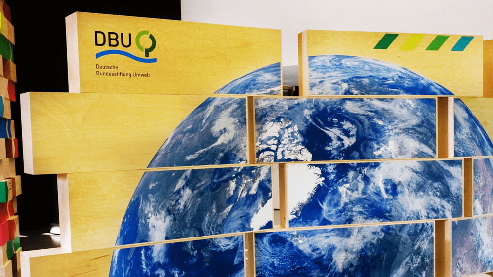 Die Introwand der Ausstellung mit einem gro&szlig;en Bild des blauen Planeten und DBU Logo.